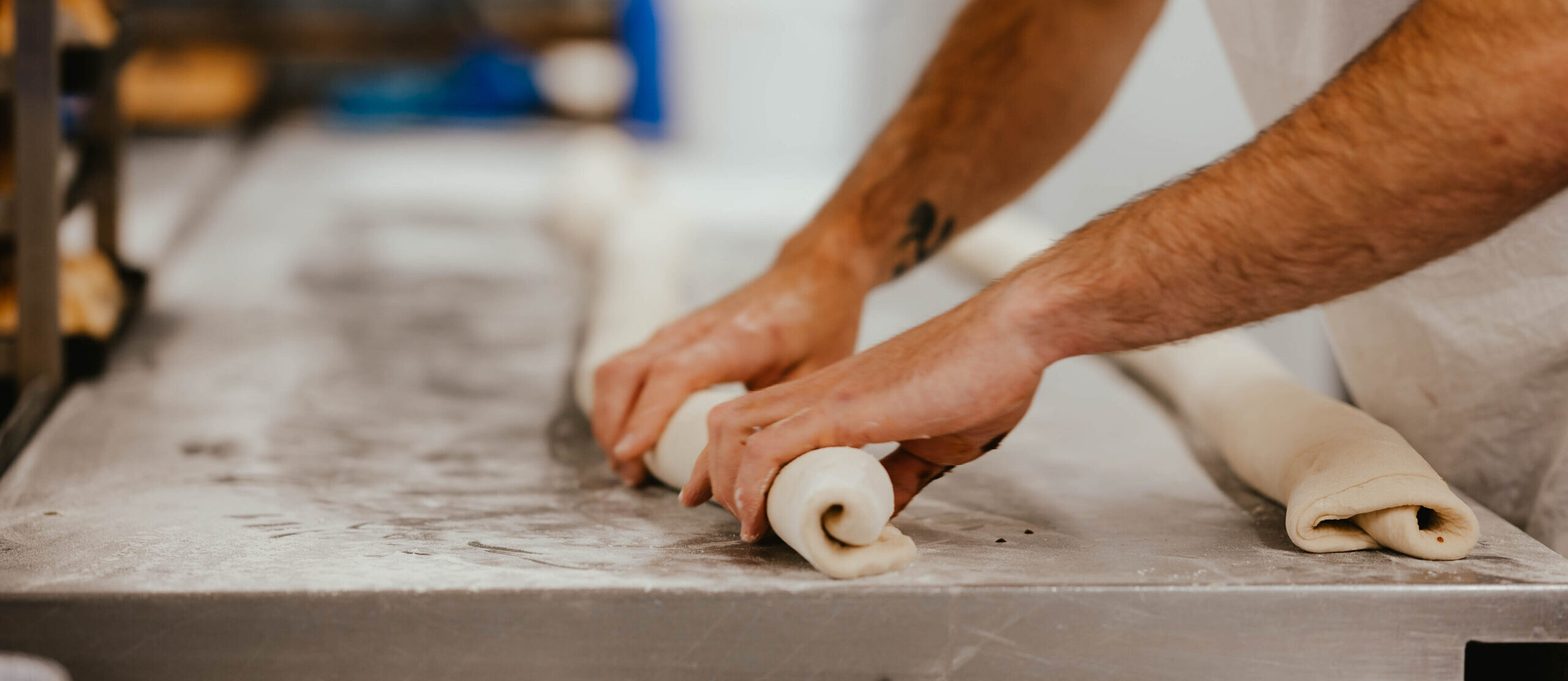 chef rolling pastry up on a worktop